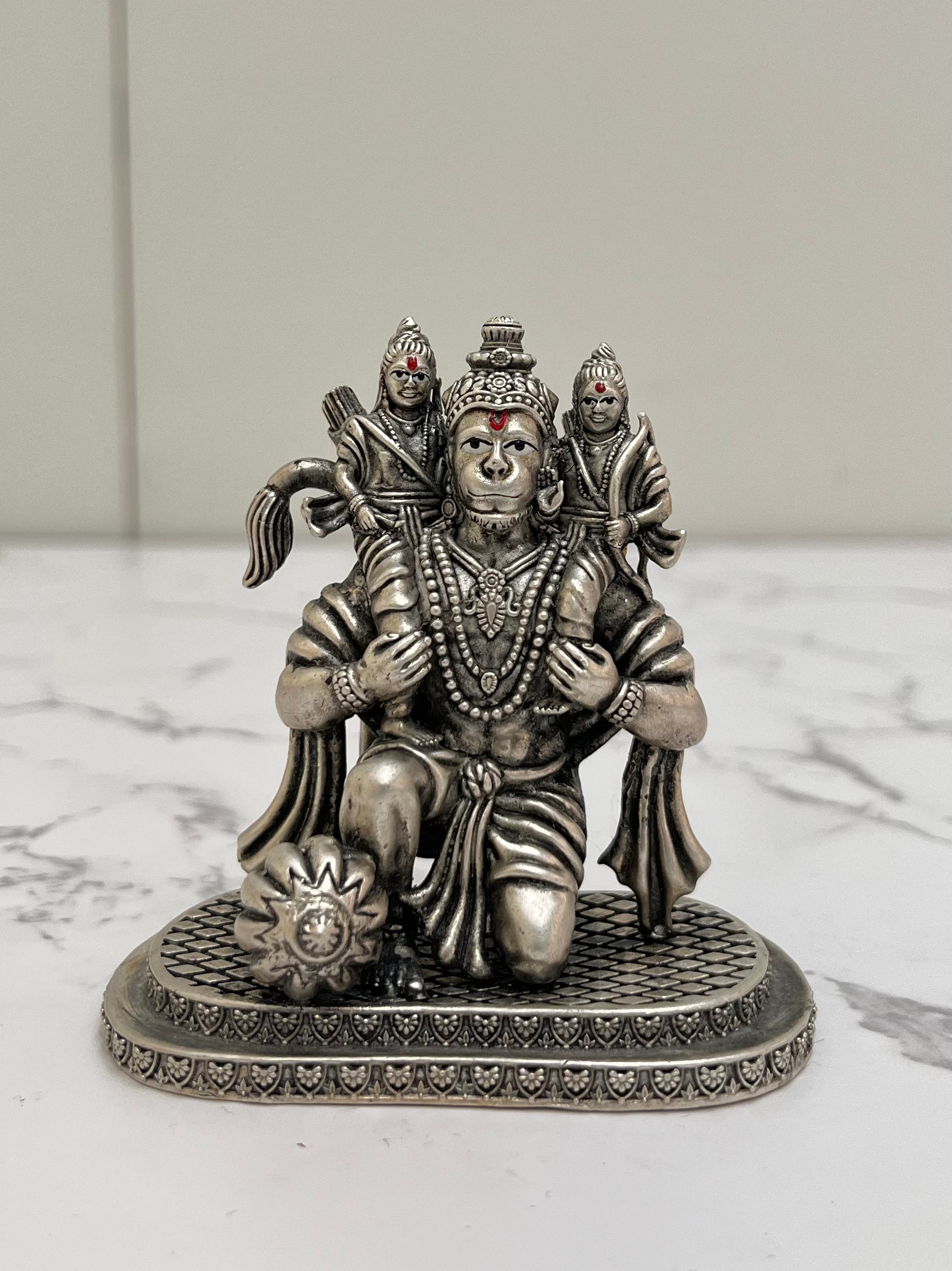 Silver statue of a deity with two attendants on a marble surface