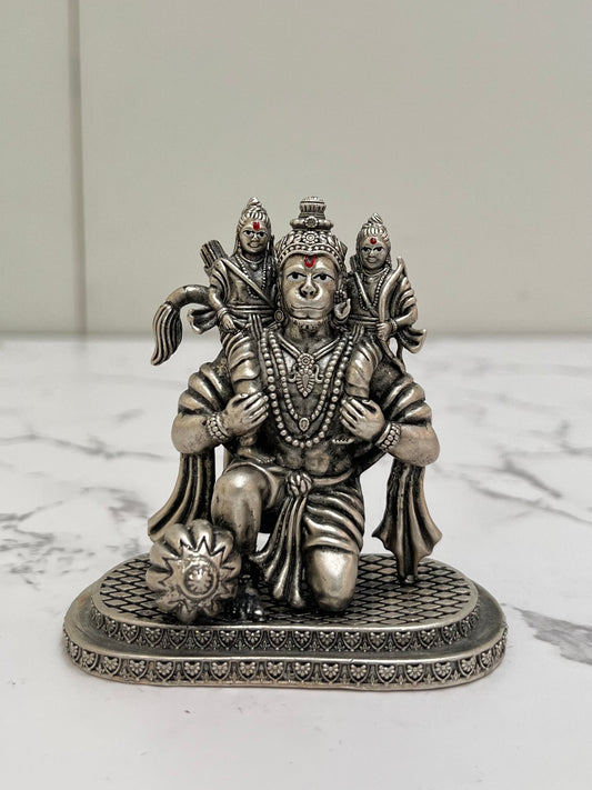 Silver statue of a deity with two attendants on a marble surface