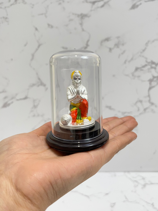 Hand holding a small figurine in a glass display case against a marble background